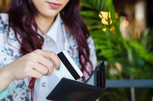 mulher retirando um cartao de credito da carteira
